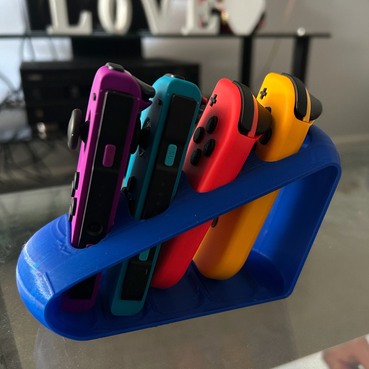 Blue 3D printed Nintendo Switch Joy-Con stand holding four coloured controllers