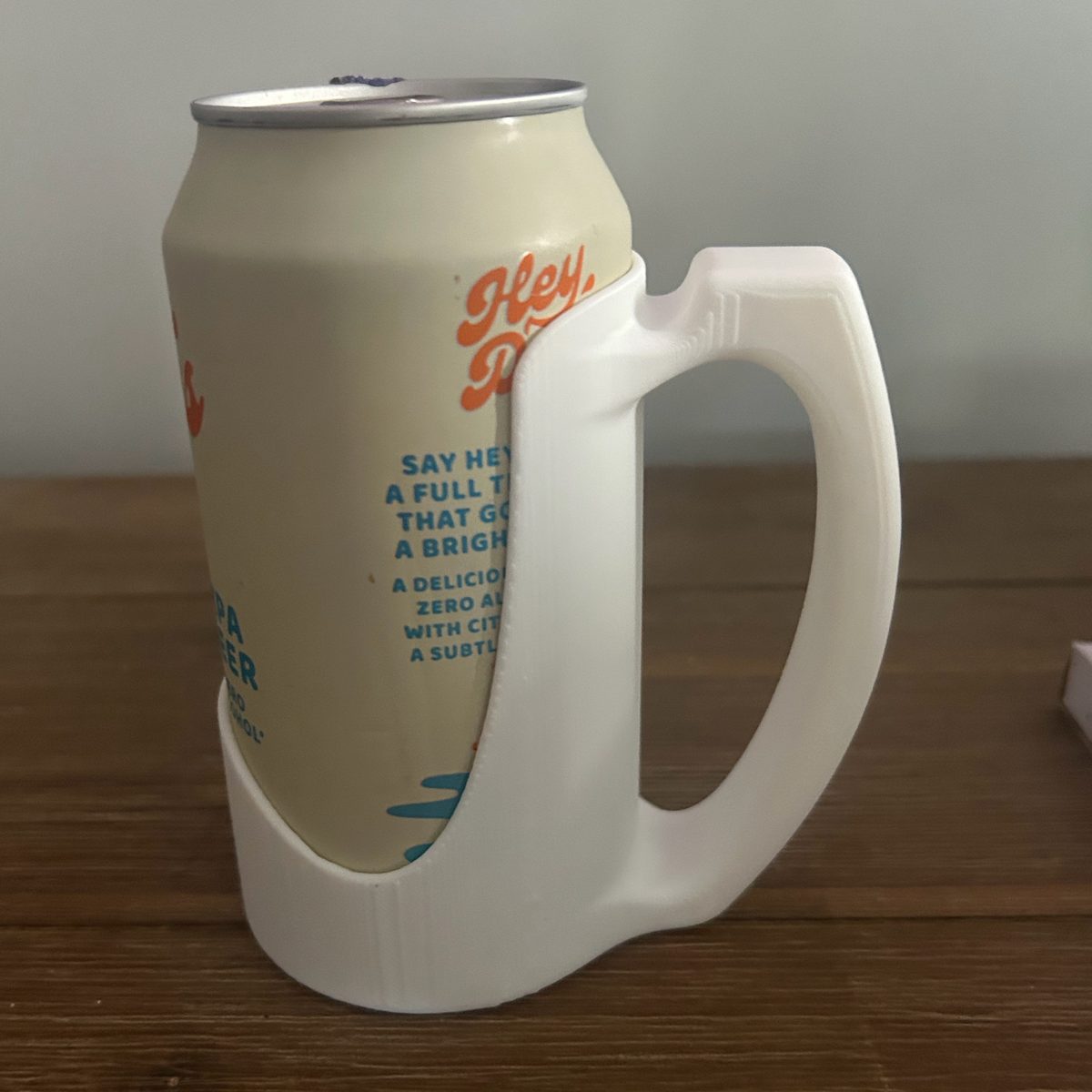 White 3D printed drink can holder with handle, holding a can