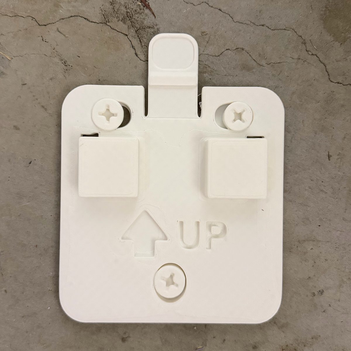 White 3D printed wall mount bracket plate with screw slots and UP arrow